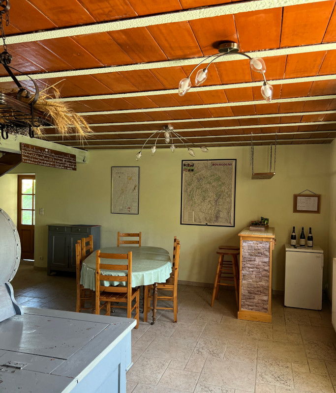La salle à manger du gîte, plafond à poutres et cartes de randonnée au mur