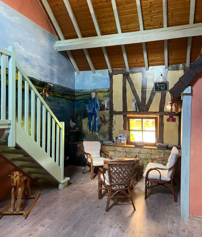 Le salon du gîte et sa fresque murale champêtre, au pied de l'escalier